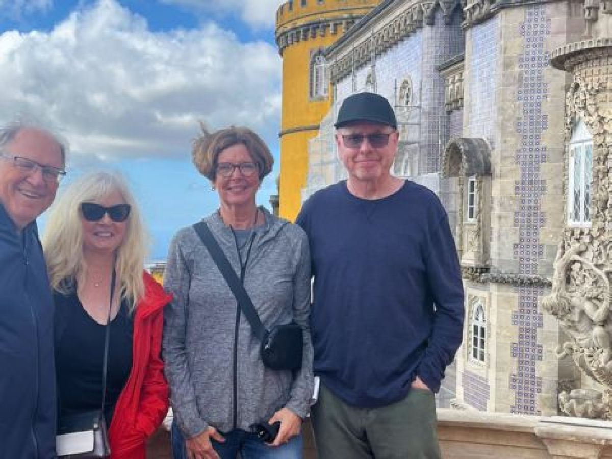 Four visitors pose in front of the colorful Pena Palace in Sintra, taken during a private tour.