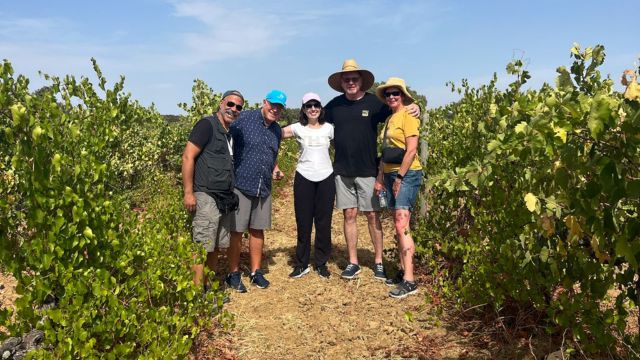 Friends posing for a photo in a vineyard during a private cork tour in Évora, Portugal, celebrating wine production.