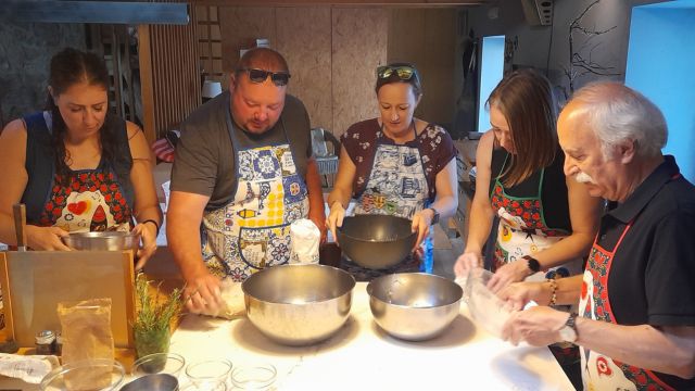 A cooking class in Portugal where a group is actively preparing bread, with hands working together on the dough.