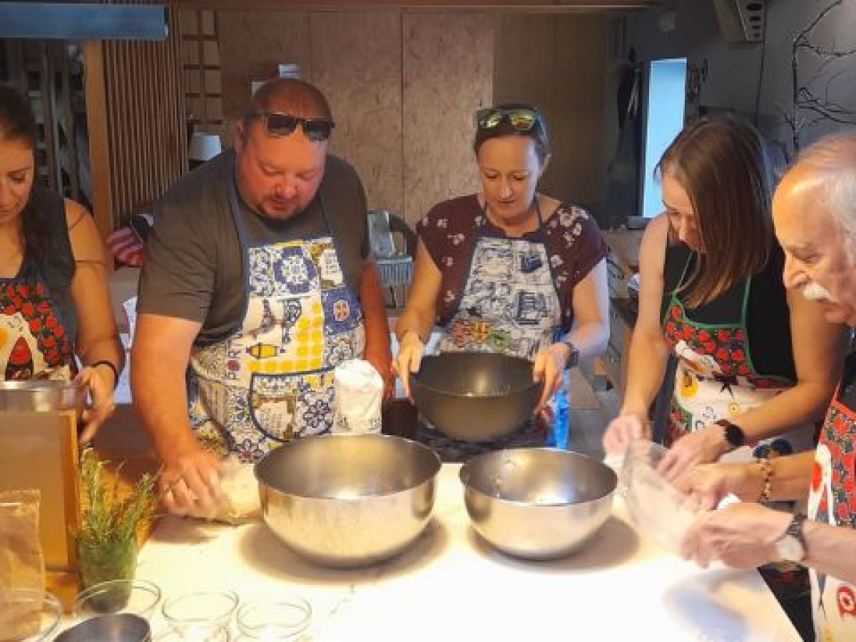 A cooking class in Portugal where a group is actively preparing bread, with hands working together on the dough.