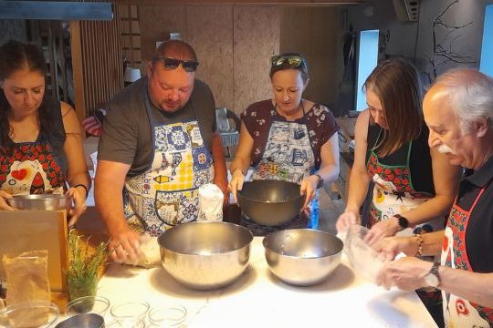 A cooking class in Portugal where a group is actively preparing bread, with hands working together on the dough.