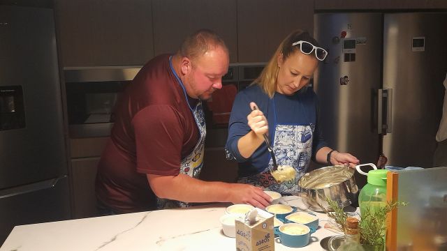 A couple participates in a cooking class in Portugal, preparing food together in a bright kitchen.