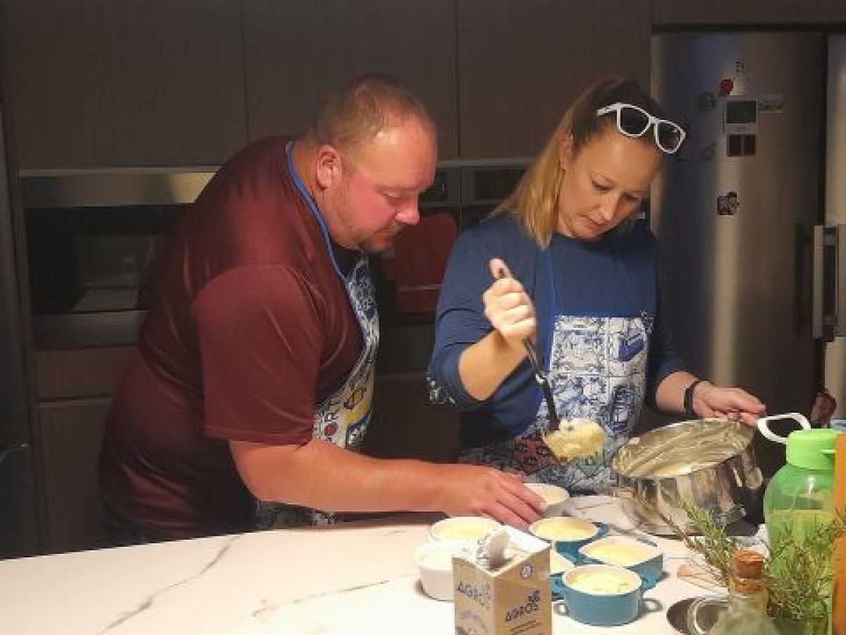 A couple participates in a cooking class in Portugal, preparing food together in a bright kitchen.