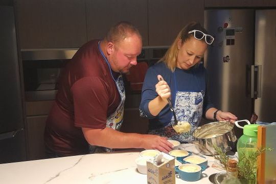 A couple participates in a cooking class in Portugal, preparing food together in a bright kitchen.
