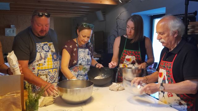 A diverse group of individuals in a Portuguese kitchen, engaged in food preparation during a cooking class.