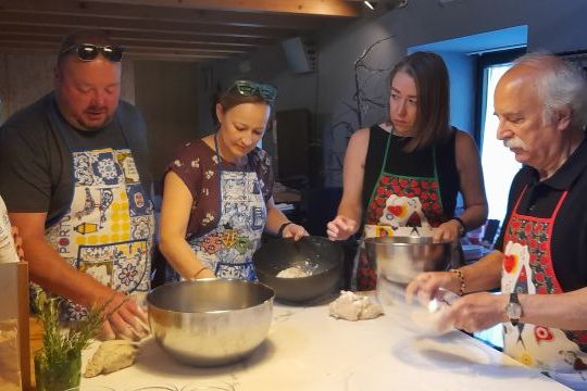 A diverse group of individuals in a Portuguese kitchen, engaged in food preparation during a cooking class.