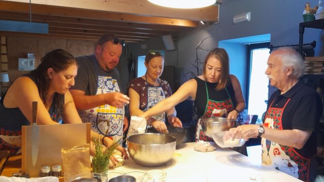 A group of participants kneading dough during a bread-making class in Portugal, focused on their culinary task.