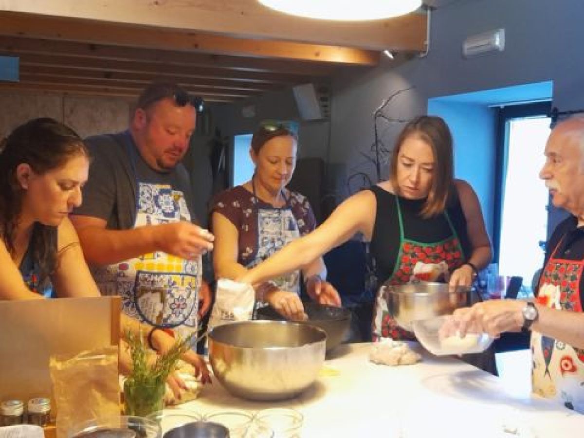 A group of participants kneading dough during a bread-making class in Portugal, focused on their culinary task.