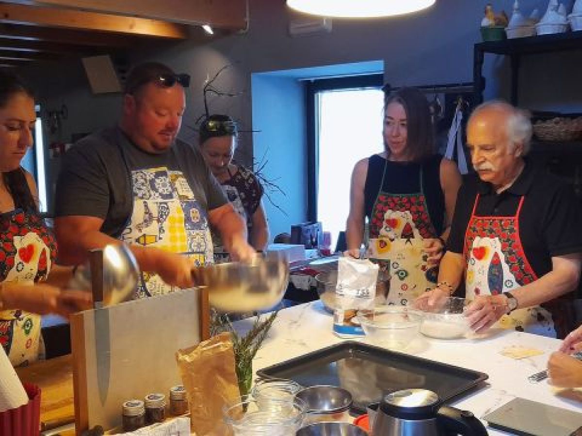 A group of people in a kitchen during a cooking class in Portugal, actively preparing various dishes together.