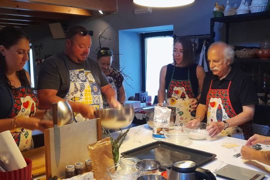 A group of people in a kitchen during a cooking class in Portugal, actively preparing various dishes together.