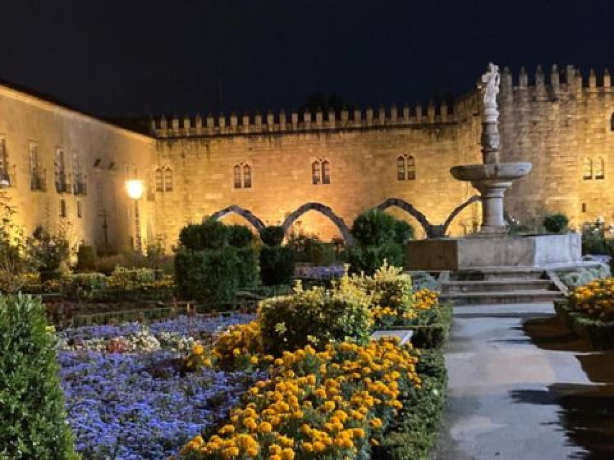 Nighttime in a Braga garden, with blooming flowers and a tranquil fountain illuminated under the stars.