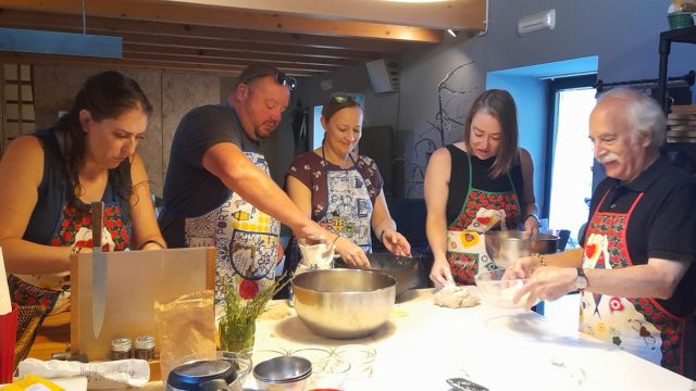 Participants in a cooking class in Portugal collaboratively preparing bread, engaged in kneading and shaping the dough.