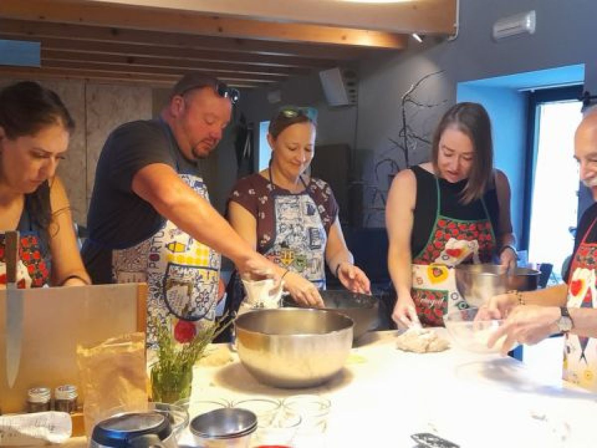 Participants in a cooking class in Portugal collaboratively preparing bread, engaged in kneading and shaping the dough.