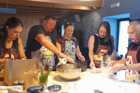 Participants in a cooking class in Portugal collaboratively preparing bread, engaged in kneading and shaping the dough.