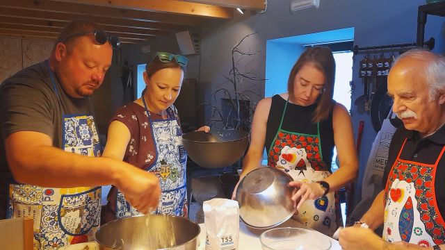 Participants in a cooking class in Portugal gather in a kitchen, collaborating to prepare a variety of foods.