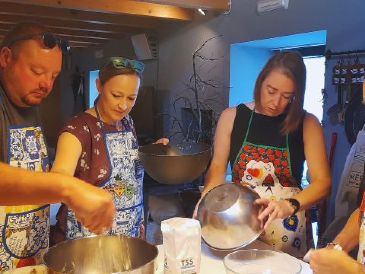 Participants in a cooking class in Portugal gather in a kitchen, collaborating to prepare a variety of foods.