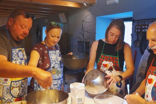 Participants in a cooking class in Portugal gather in a kitchen, collaborating to prepare a variety of foods.